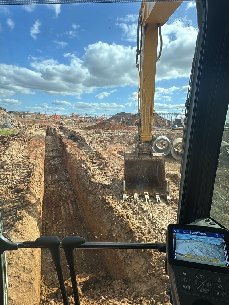 View from an excavator cab: trench dug and stormwater pipes stacked ready
